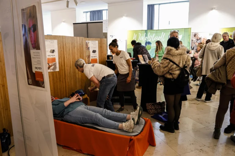 Person liegt auf einer Behandlungsliege, umgeben von Besuchenden