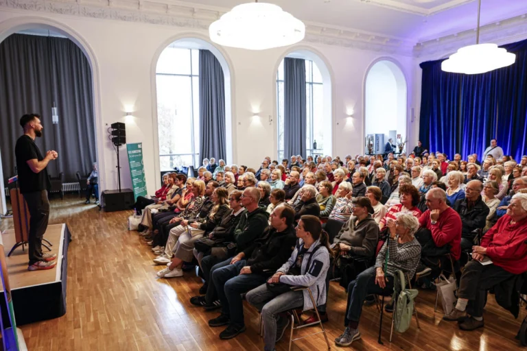 Publikum sitzt in einem Saal bei einer Veranstaltung