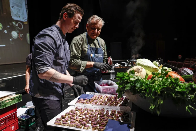 Zwei Personen richten kleine Speisen an einem Veranstaltungstisch an