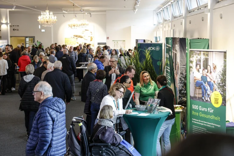 Besucherinnen und Besucher stehen an Stehtischen im Foyer einer Veranstaltung