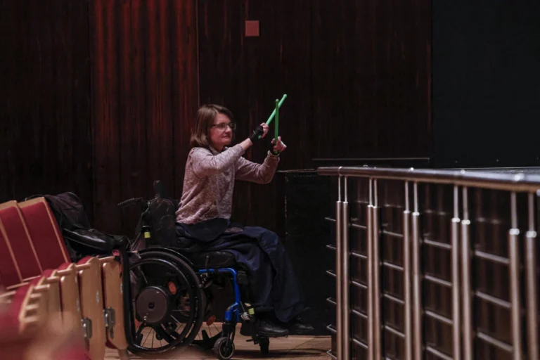 Person im Rollstuhl beteiligt sich an einer Bühnenaktion mit Bewegungselementen