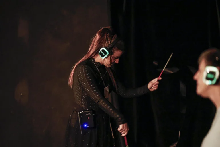 Person trägt Kopfhörer und gibt Anweisungen auf einer Bühne