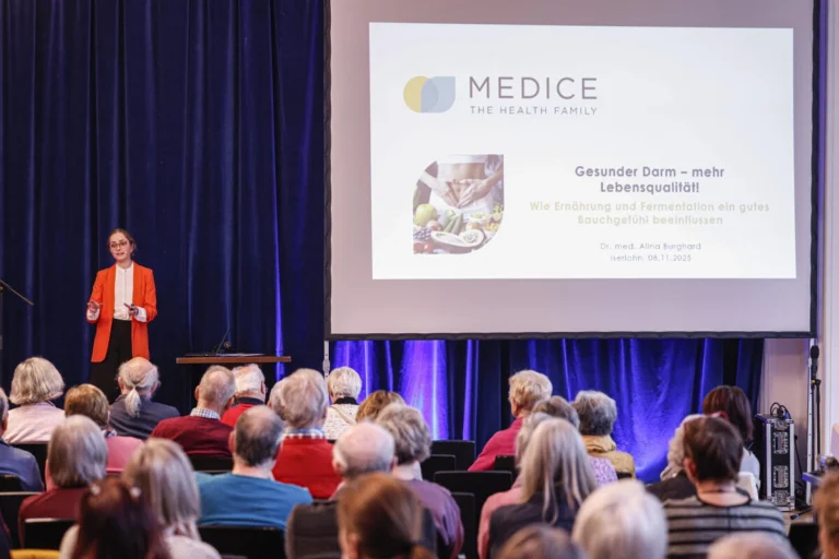 Publikum hört einem Vortrag vor einer Präsentationsfolie zu