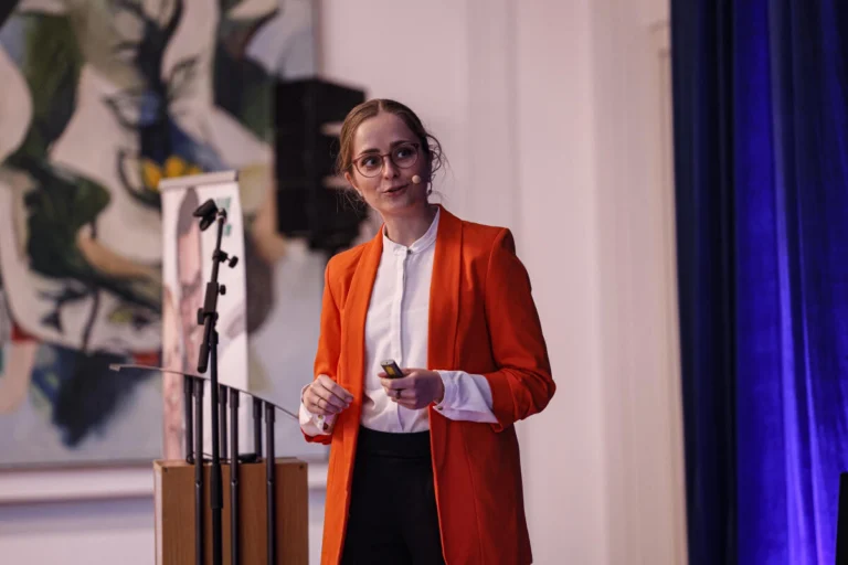 Person spricht als Referentin auf einer Bühne