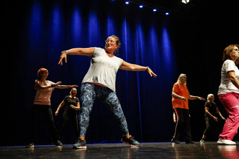 Gruppe an Personen führen eine sportliche Übung auf einer beleuchteten Bühne aus