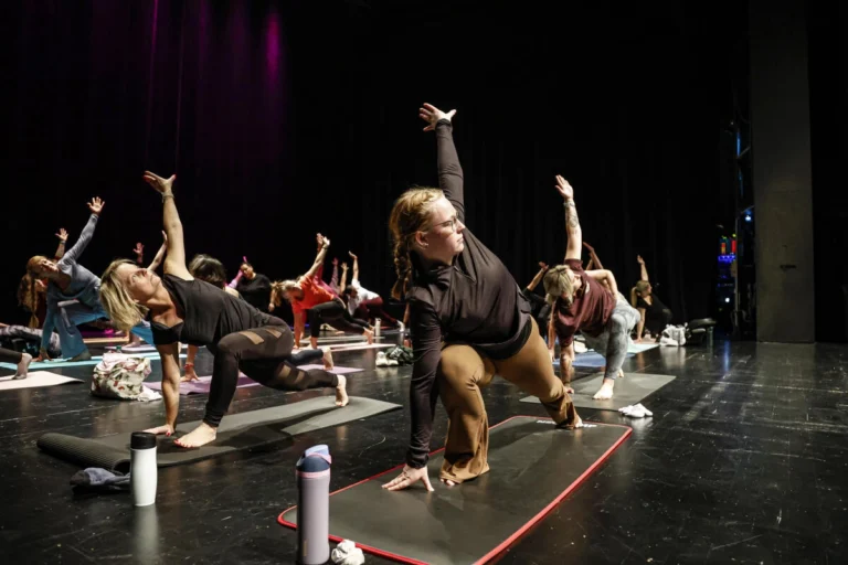 Mehrere Personen führen Yoga-Übungen auf einer Bühne aus