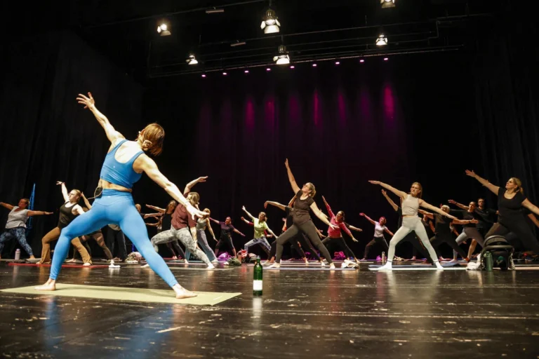 Mehrere Personen führen Yoga-Übungen auf einer Bühne aus