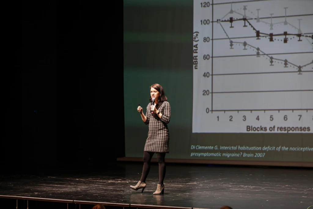 Vortrag auf einer Bühne mit Präsentationsfolie im Hintergrund
