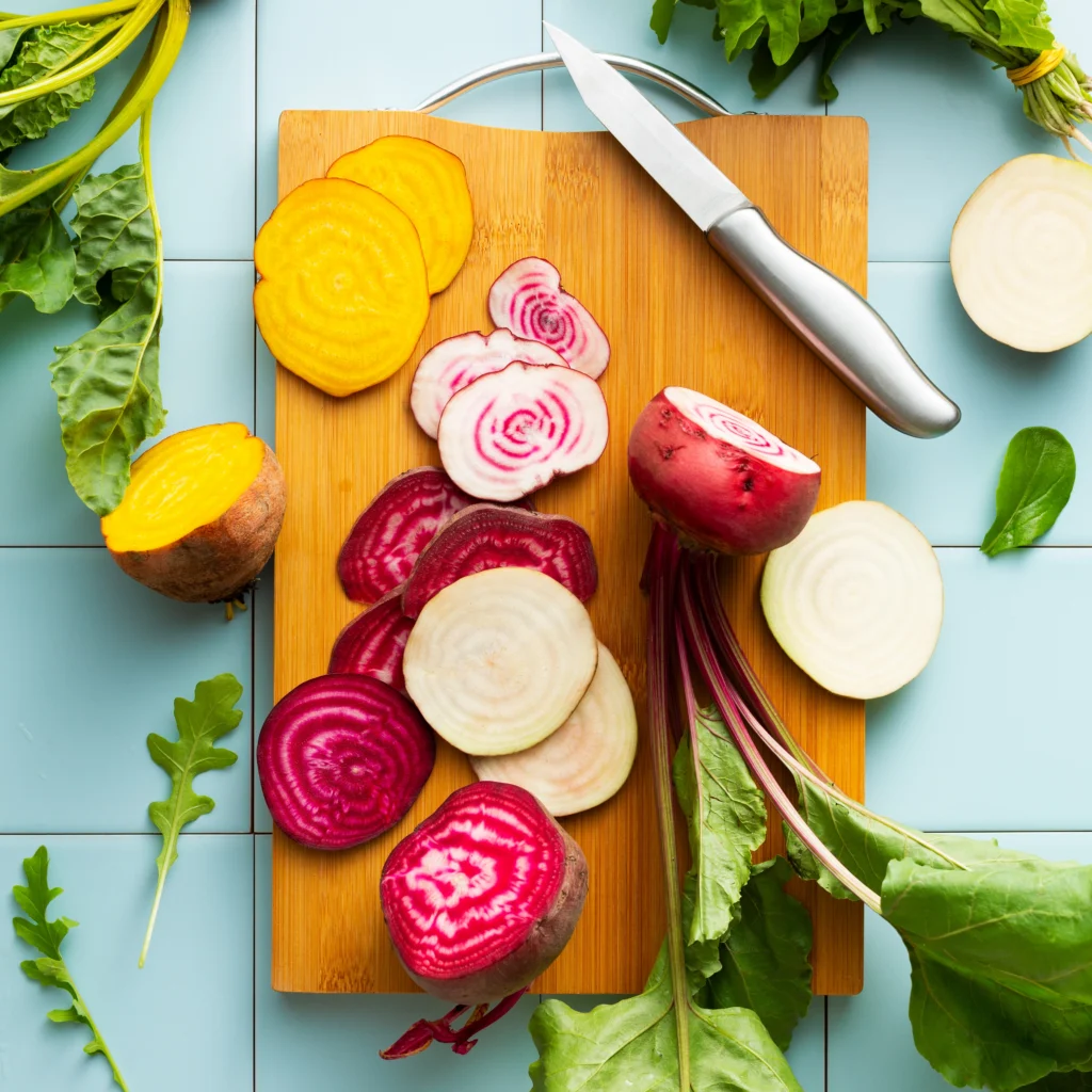 Aufgeschnittene Rote und Gelbe Bete auf einem Schneidebrett mit Messer